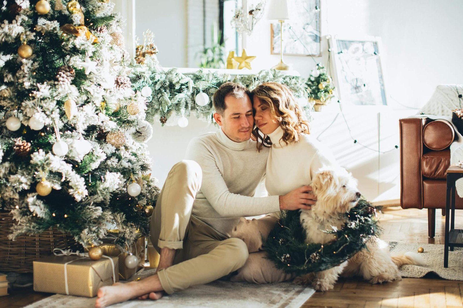 Couple and dog sitting by the Christmas tree in a festive home setting.